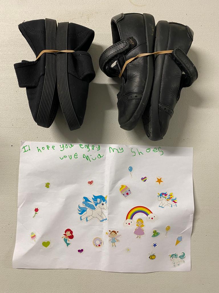 Two pairs of shoes, accompanied by a letter written by a child saying 'I hope you enjoy my shoes'. 
